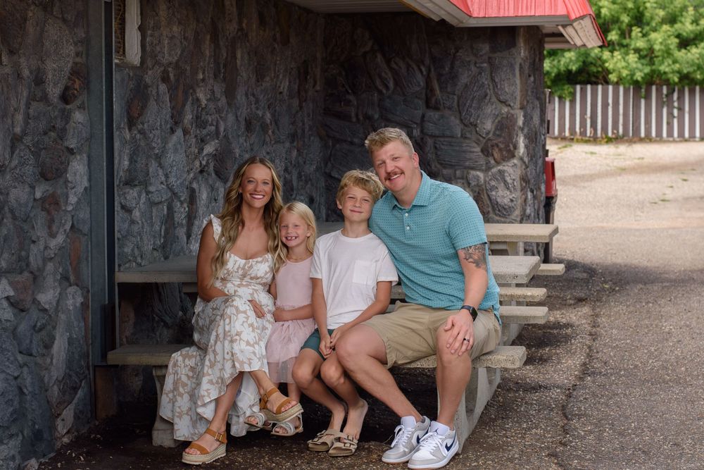A relaxed family gathering outside a rustic building on a sunny day.