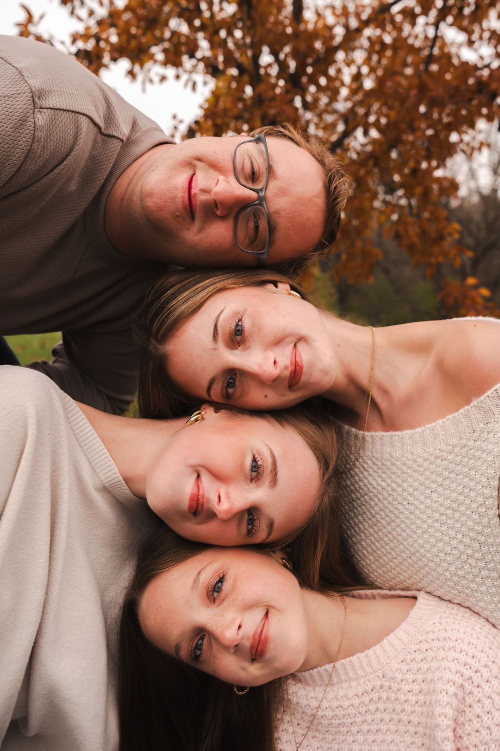 Creative fall family portrait with everyone lying down among autumn leaves.