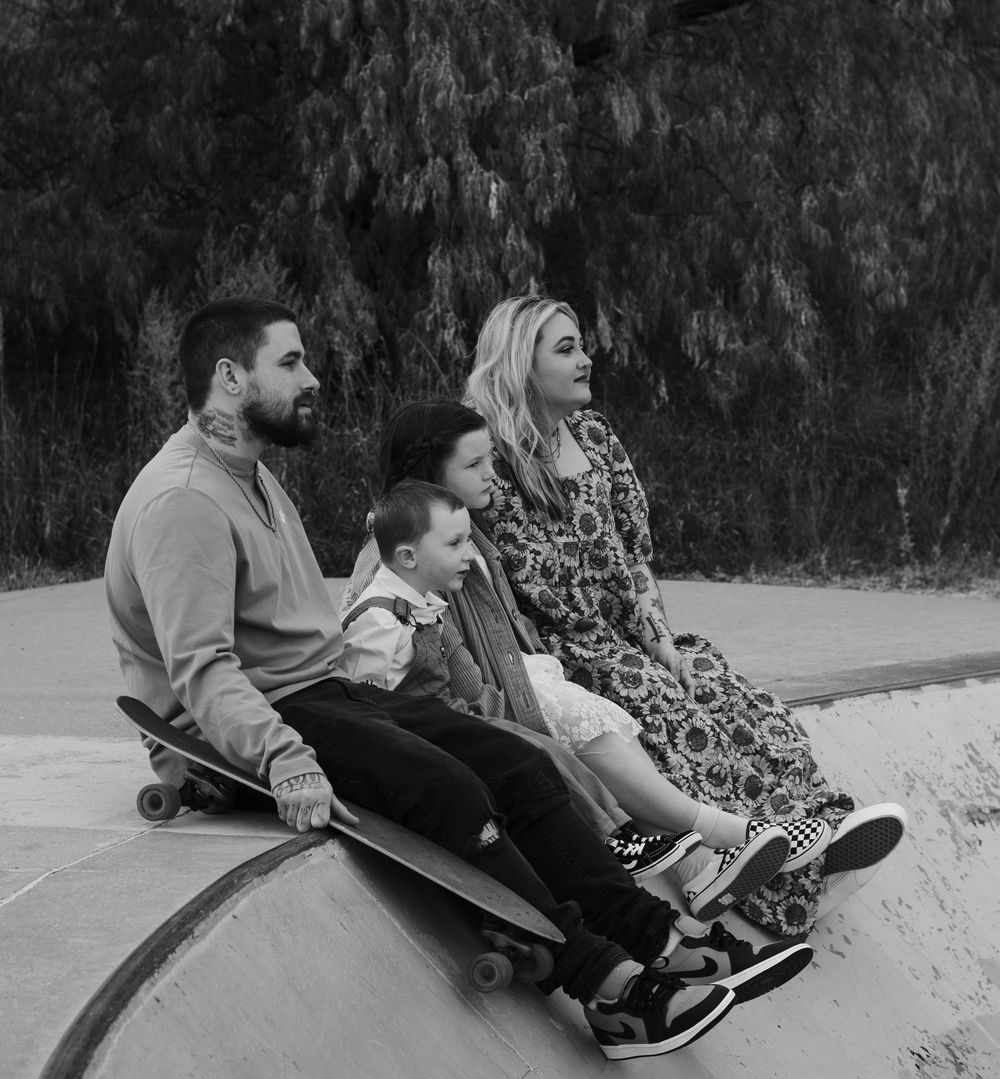 A sequence of black and white photos showing two people sliding down a concrete slope on skateboards.