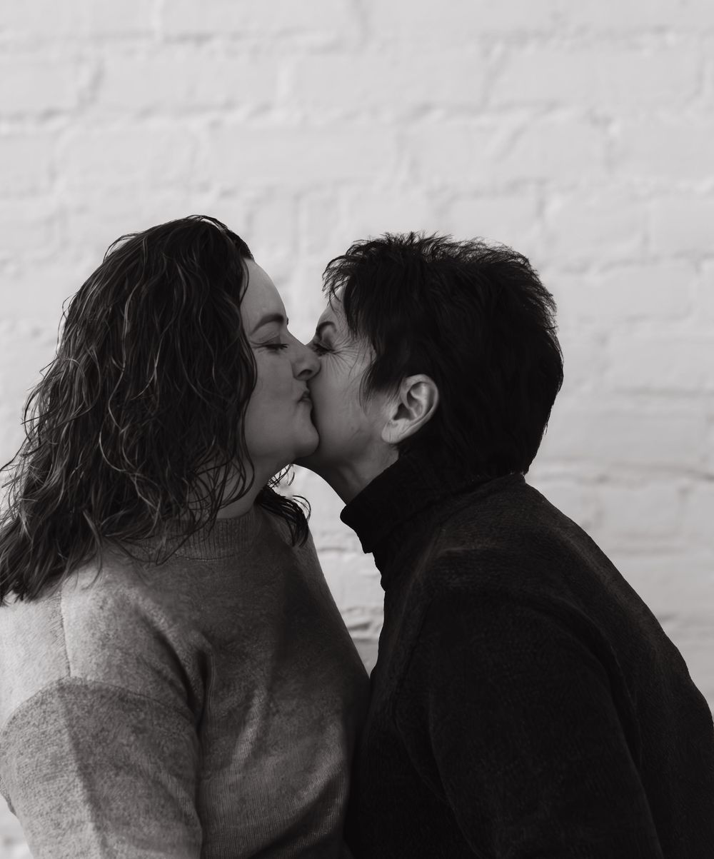 Intimate black and white portraits showing tender moments against a white brick wall background.