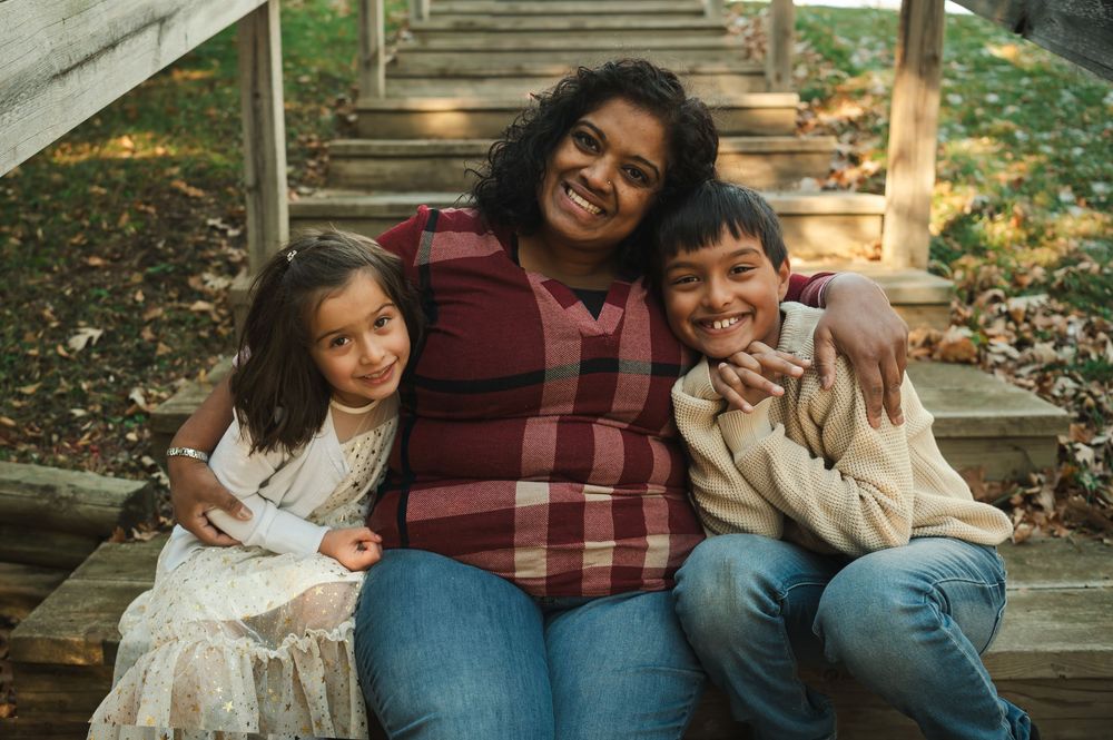 Family portrait session on wooden steps surrounded by fall foliage.