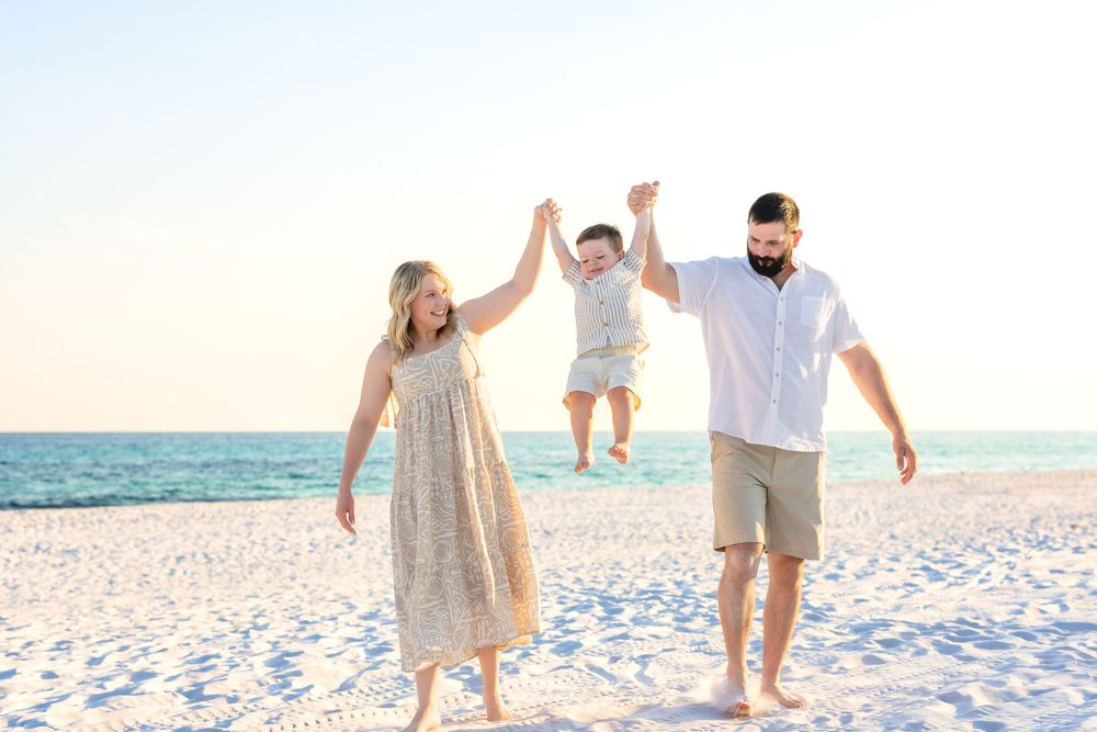 Family enjoying a sunset walk together along a pristine white sand beach with ocean waves in the background.