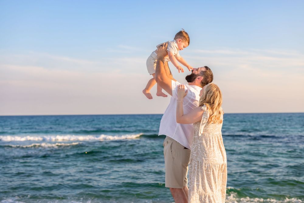 Family portraits captured along shoreline with ocean waves and golden sunset light.
