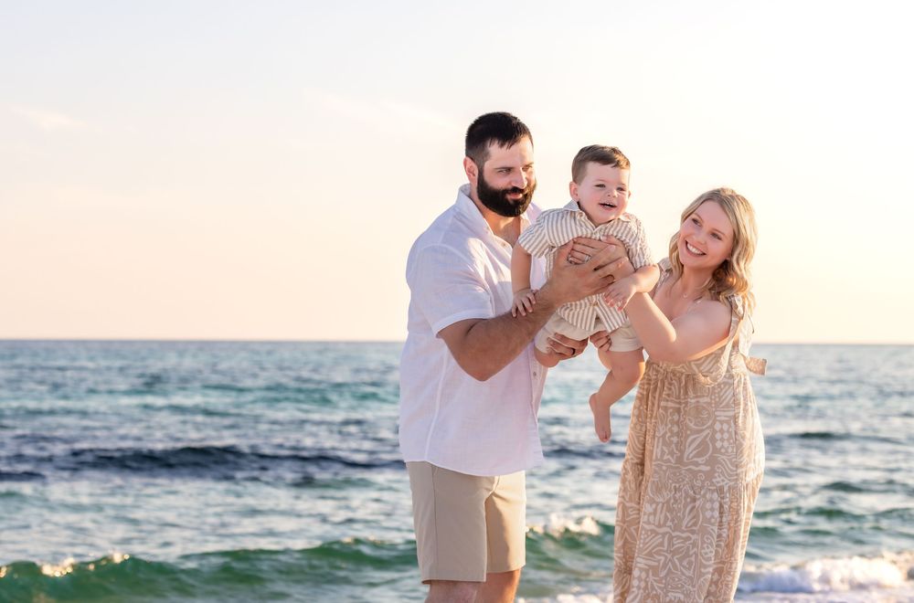 A family plays together on a sunny beach at sunset with waves and sand in the background.