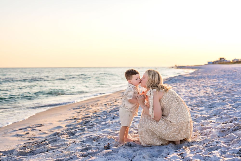 A couple shares a romantic moment together on a sandy beach during sunset.