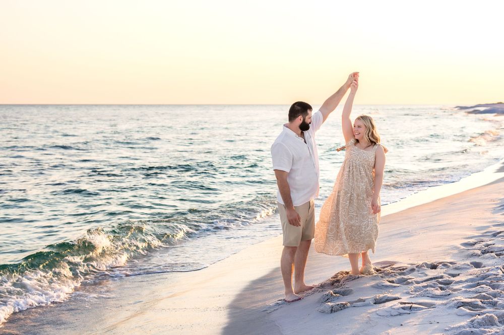 Family holding hands while walking along the shoreline at sunset with gentle waves rolling in.
