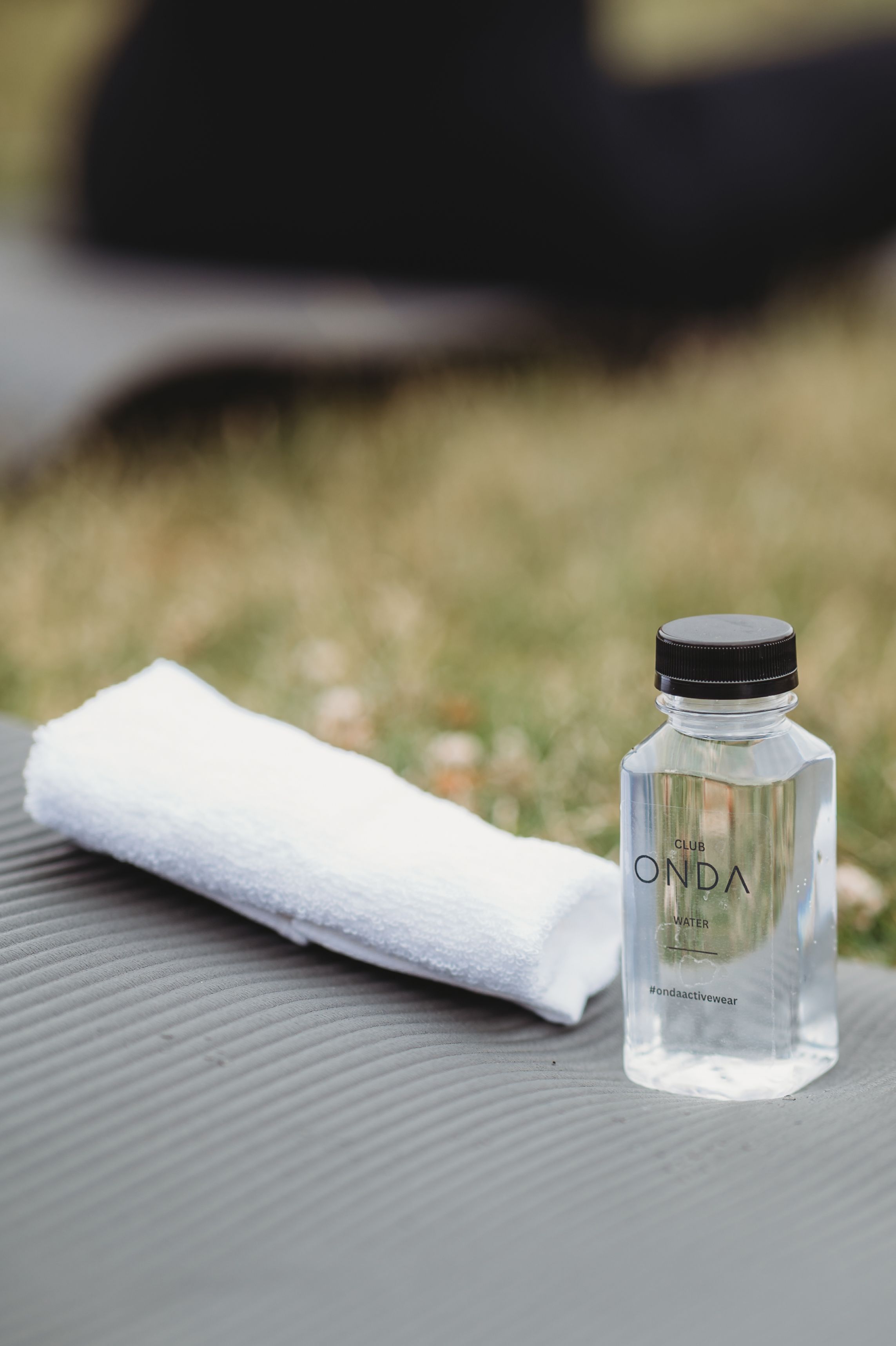 Product photography of white towels and glass containers on textured gray surface.