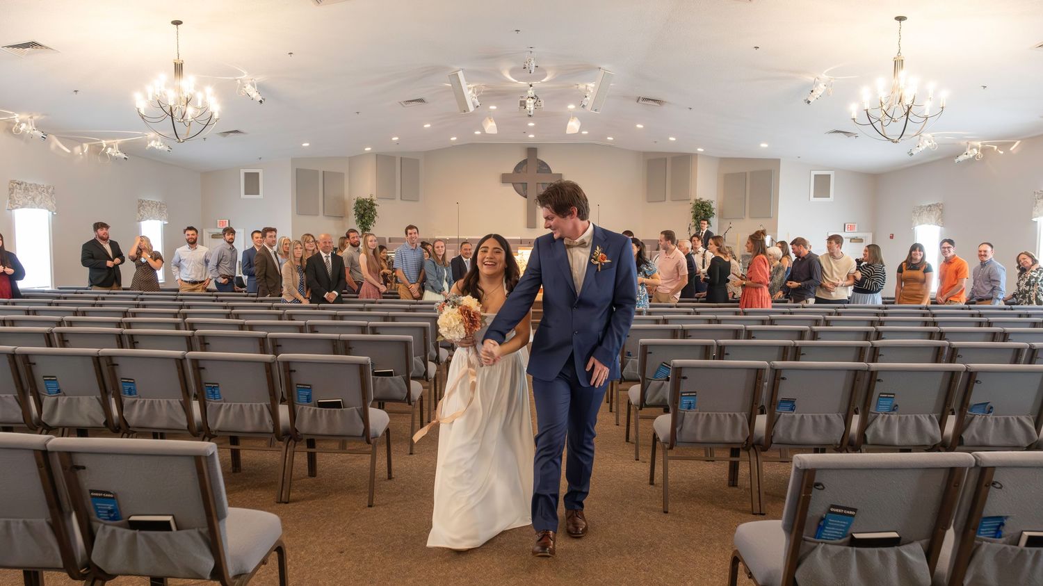 A church ceremony setting with orange floral arrangements and greenery decorating the altar steps.