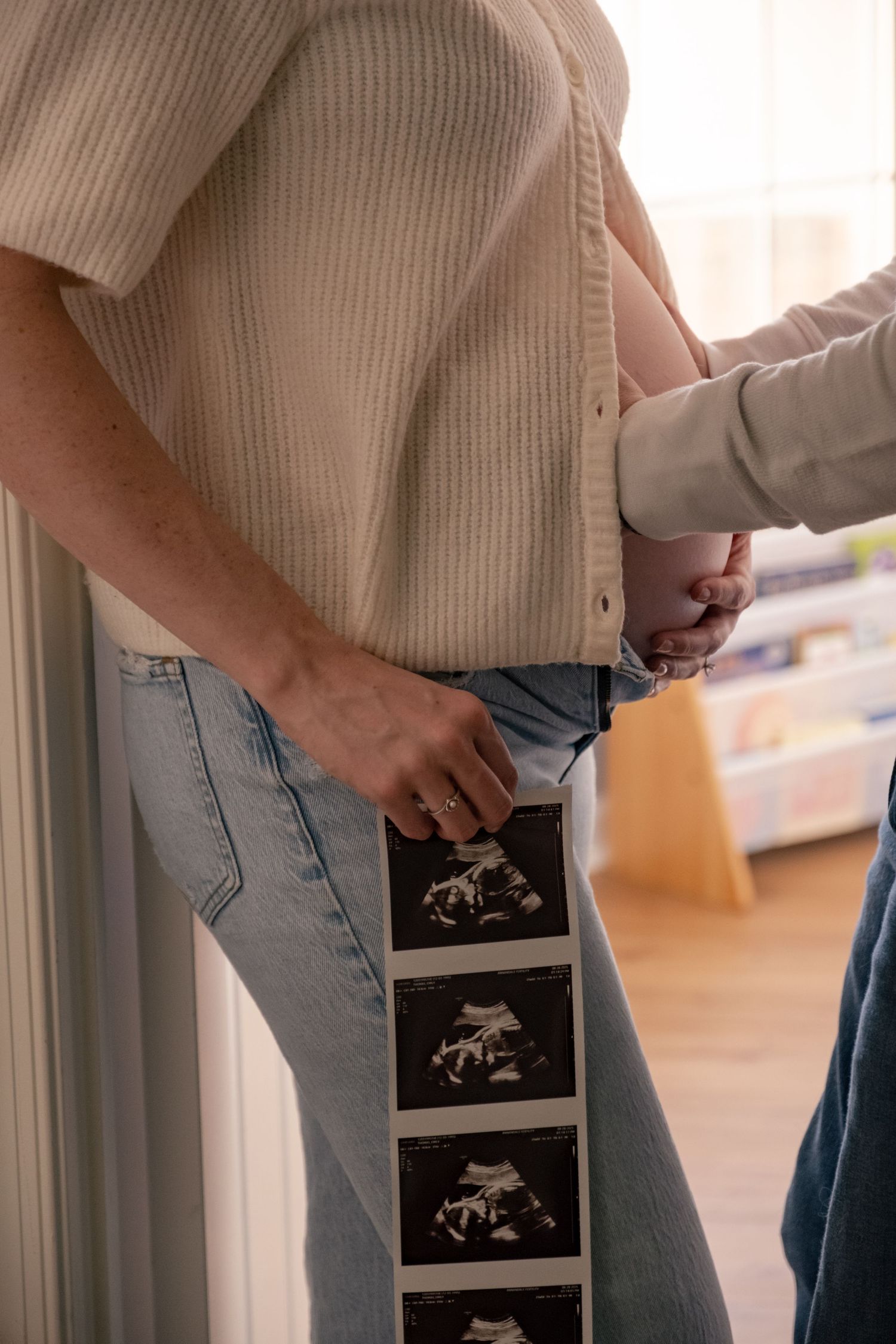 Close-up sequence showing someone tucking a cream colored sweater into light wash jeans.