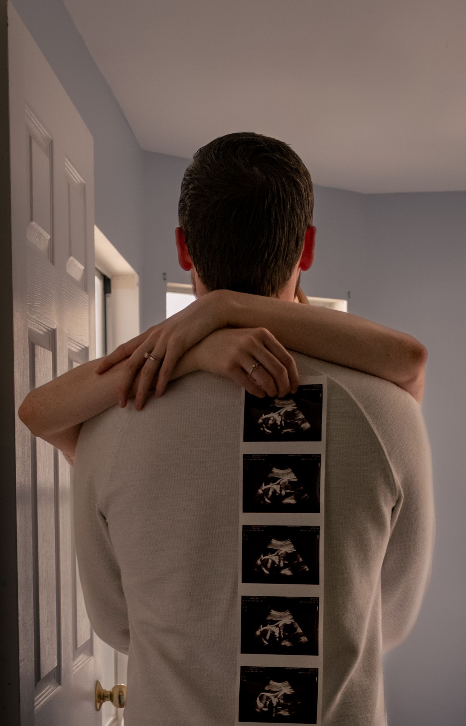 A sequence of photos showing someone in a beige sweater looking at framed artwork on a white wall.