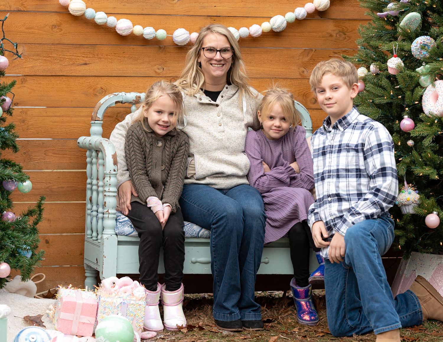 Family members sitting together on wooden steps decorated with holiday greenery and Christmas decor.