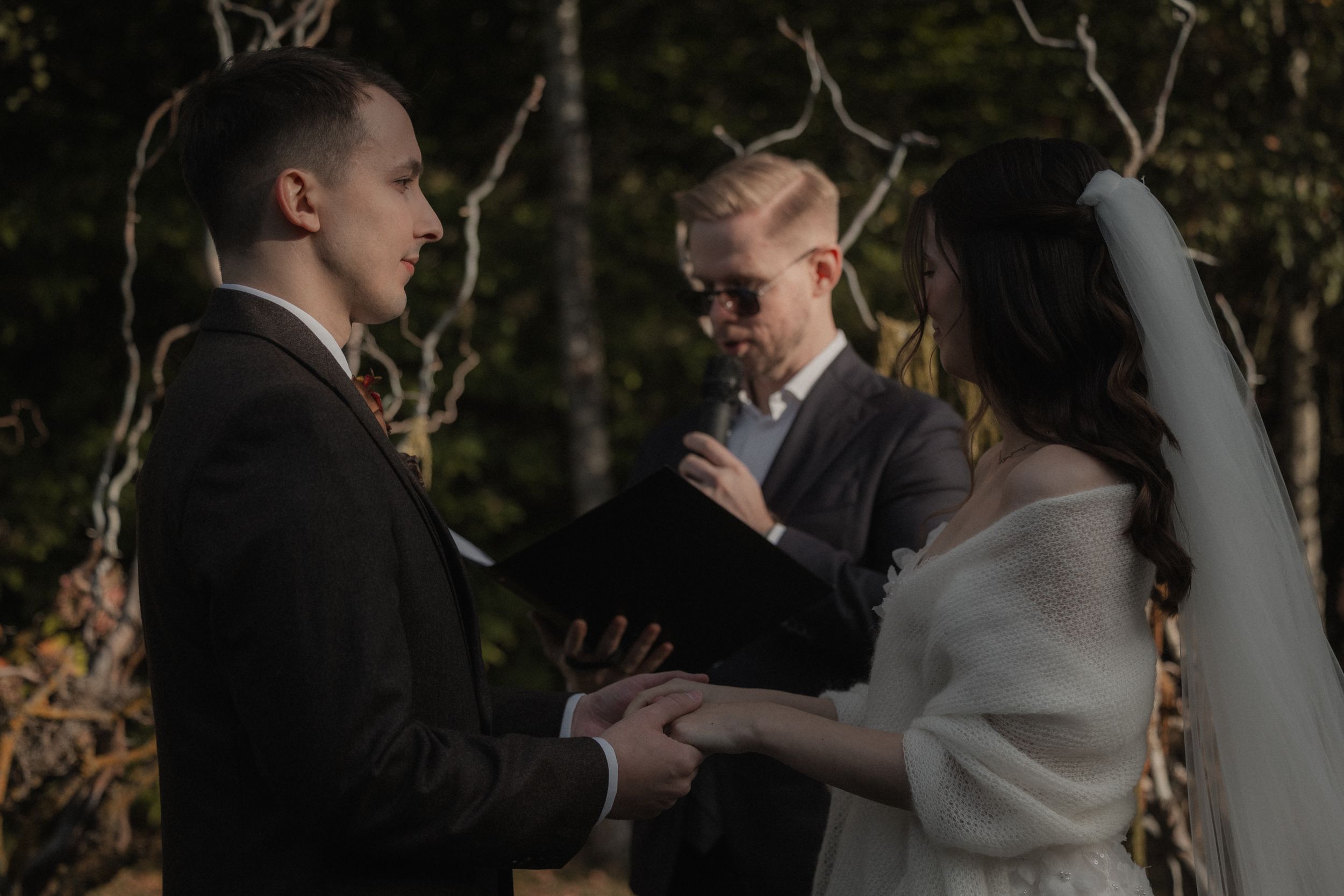 A bride and groom share an intimate dance moment surrounded by trees at their outdoor wedding celebration.