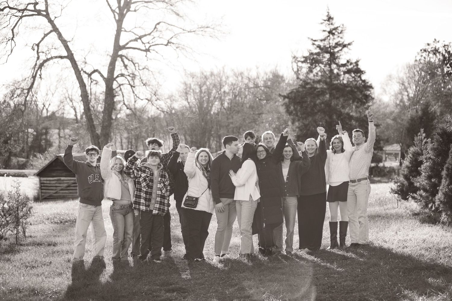 extended family cheering and taking a photo together at a christmas tree farm