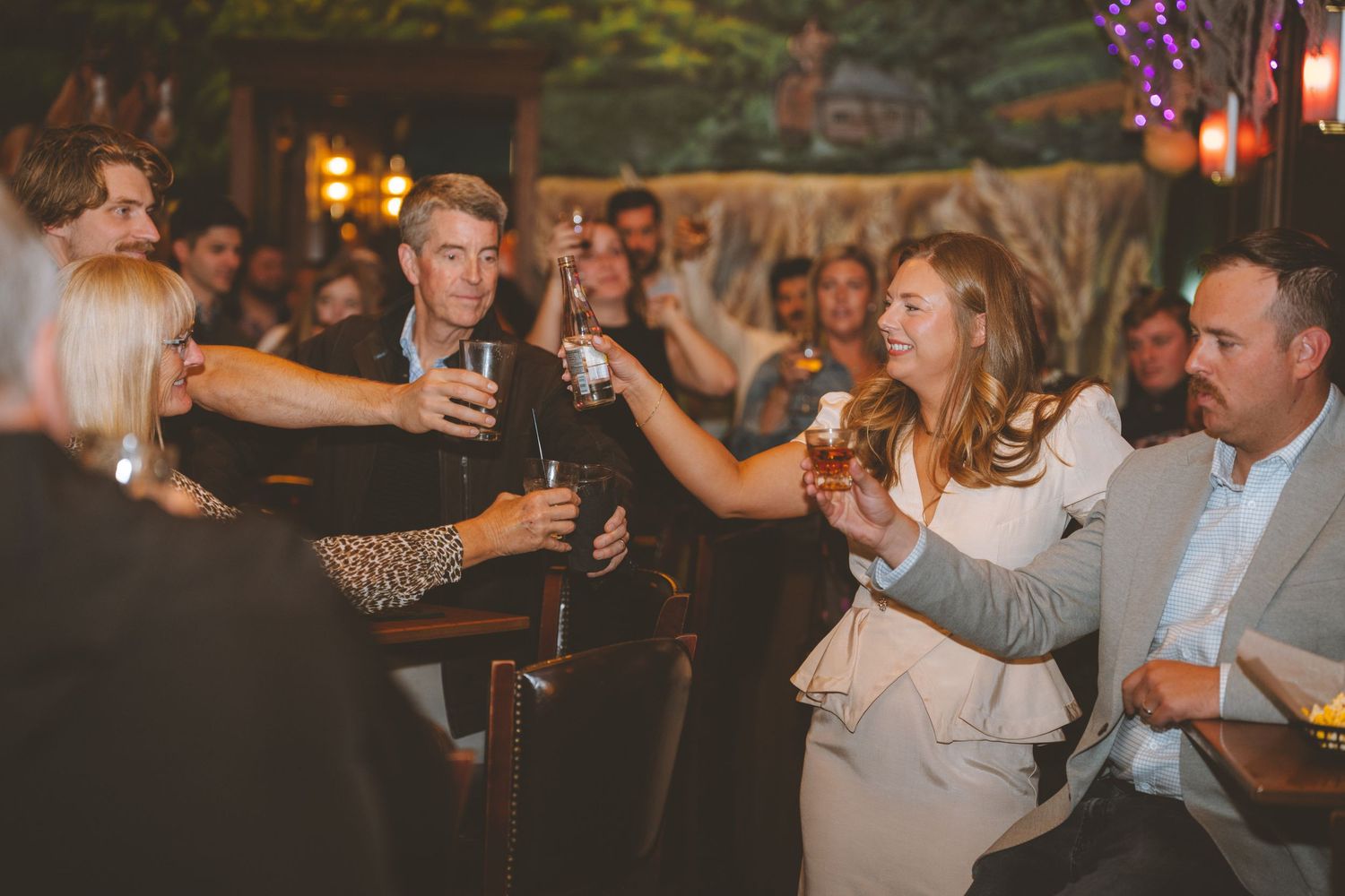 A group of people toasting with drinks at an evening social gathering.