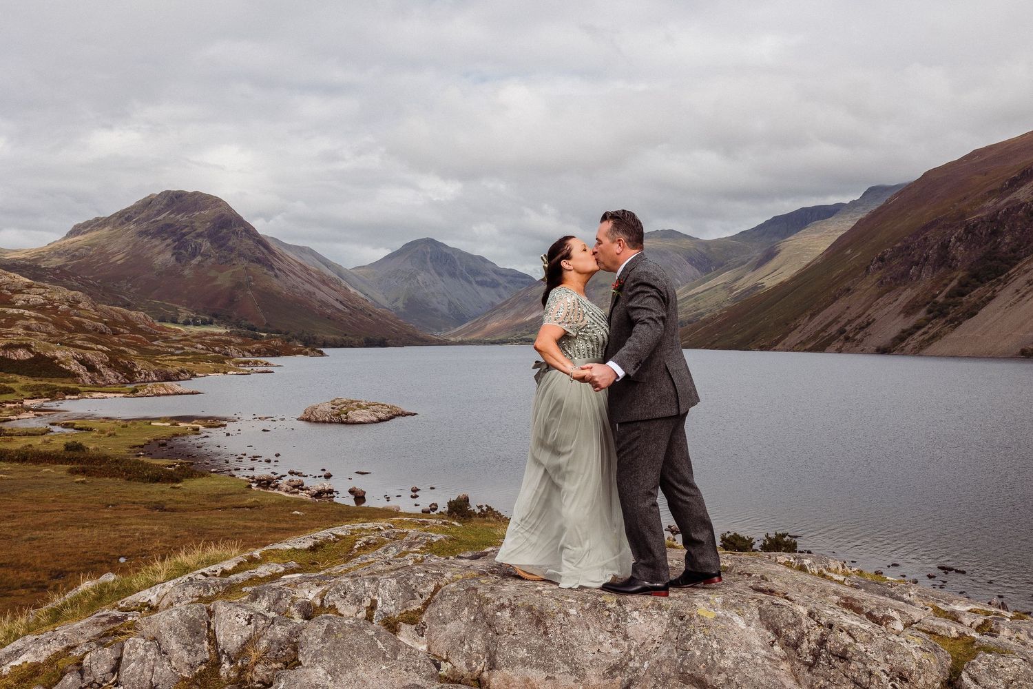 A couple shares a romantic moment overlooking a scenic mountain lake landscape in the wilderness.