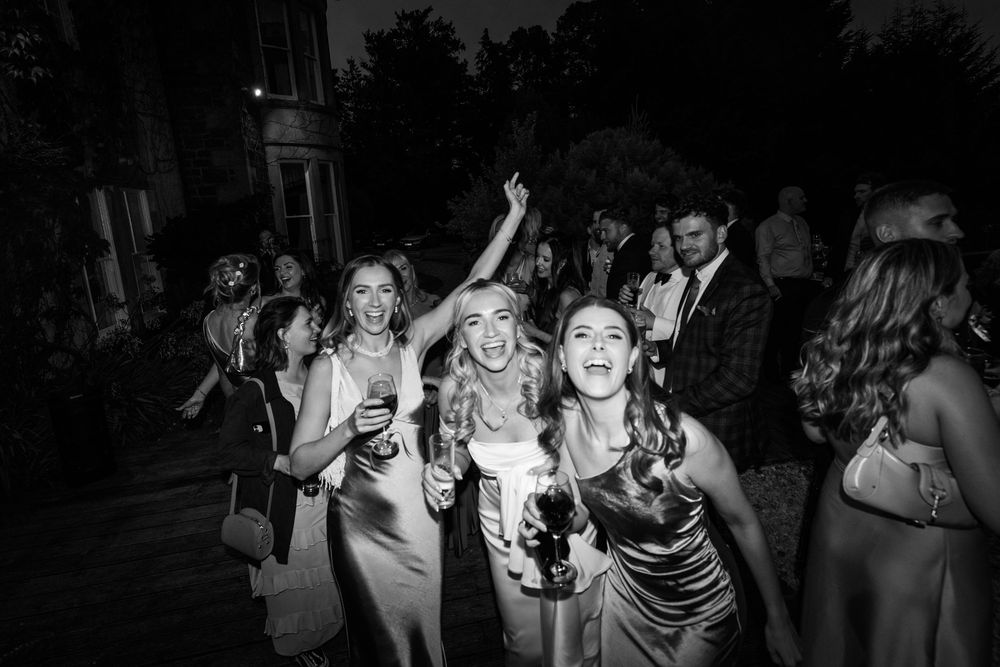 People dancing and celebrating at a lively nighttime party with glowing lights and energetic atmosphere.