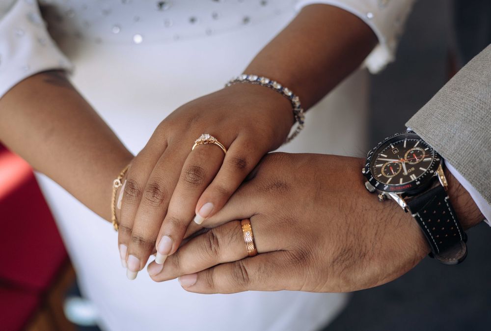 Close-up of hands wearing wedding rings during a romantic moment at a wedding ceremony.