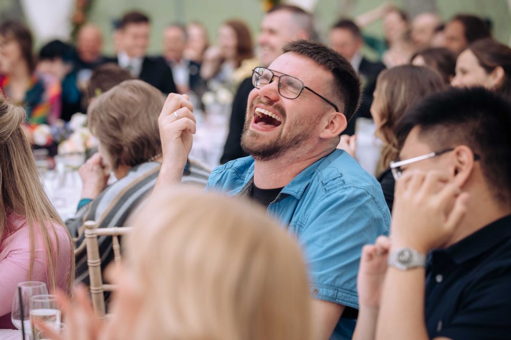 A group of people laugh together while sitting in an audience during an event.