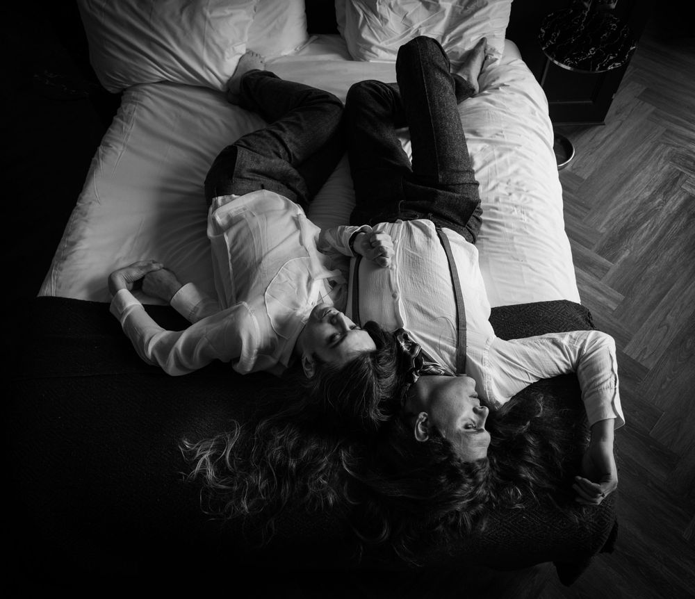 Black and white photo of people lying on the floor in a circular formation with their heads together.