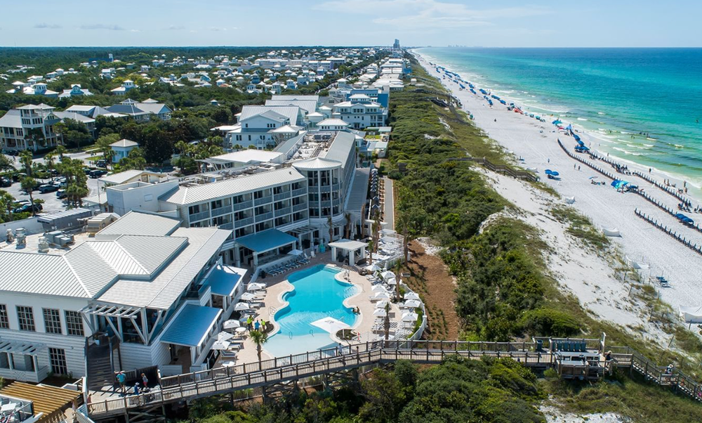 Aerial view of beachfront resort with pool overlooking white sand beaches and turquoise waters in Florida.