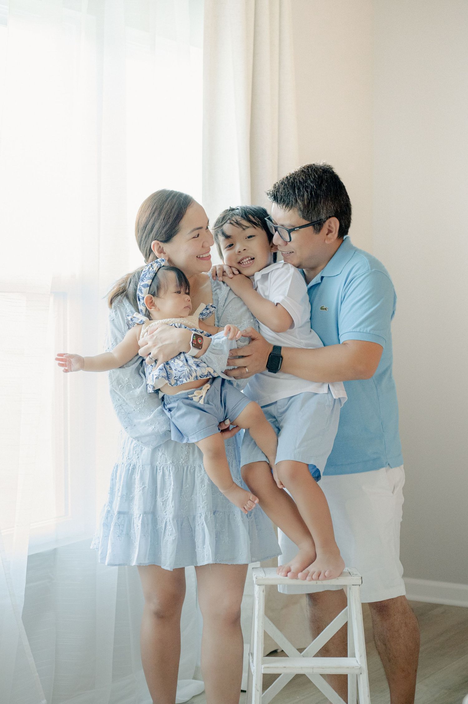 Light and airy studio photography showing tender family moments in coordinated blue and white outfits.