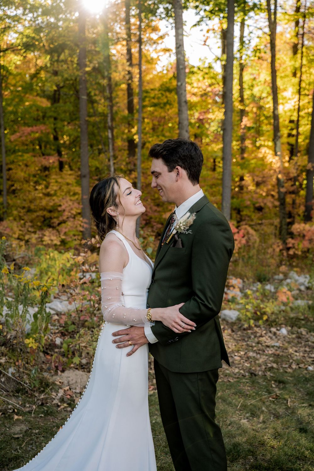 A romantic wedding photoshoot in a sunlit autumn forest with golden foliage in the background.