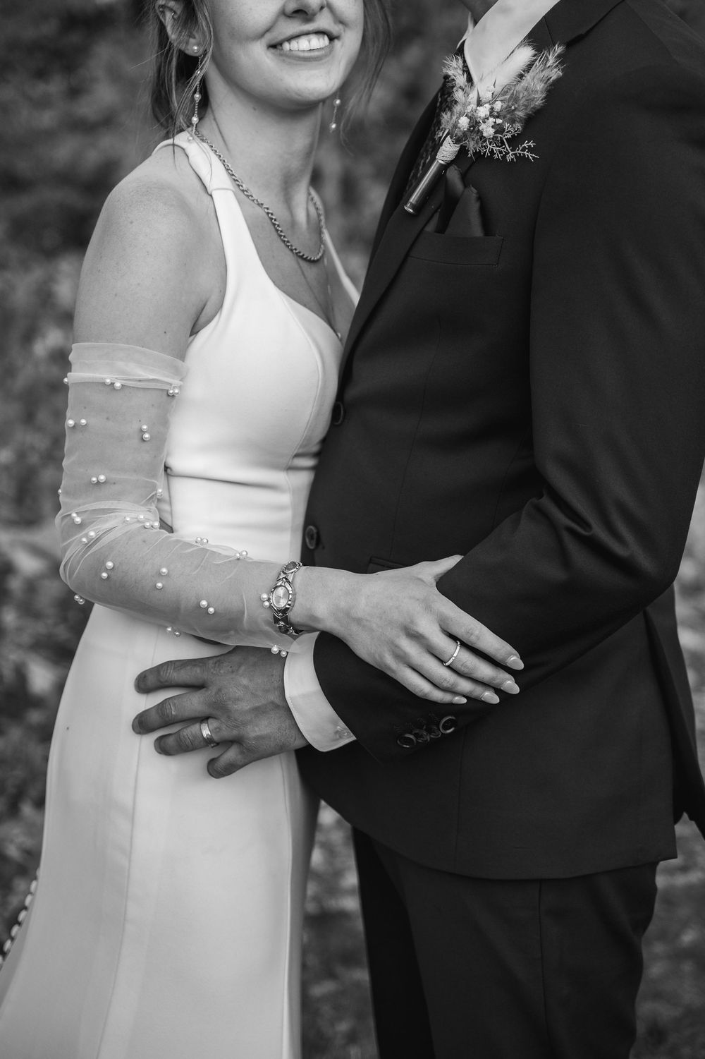 Black and white wedding photo series showing romantic close-up details of a bride in a white dress embracing her groom.