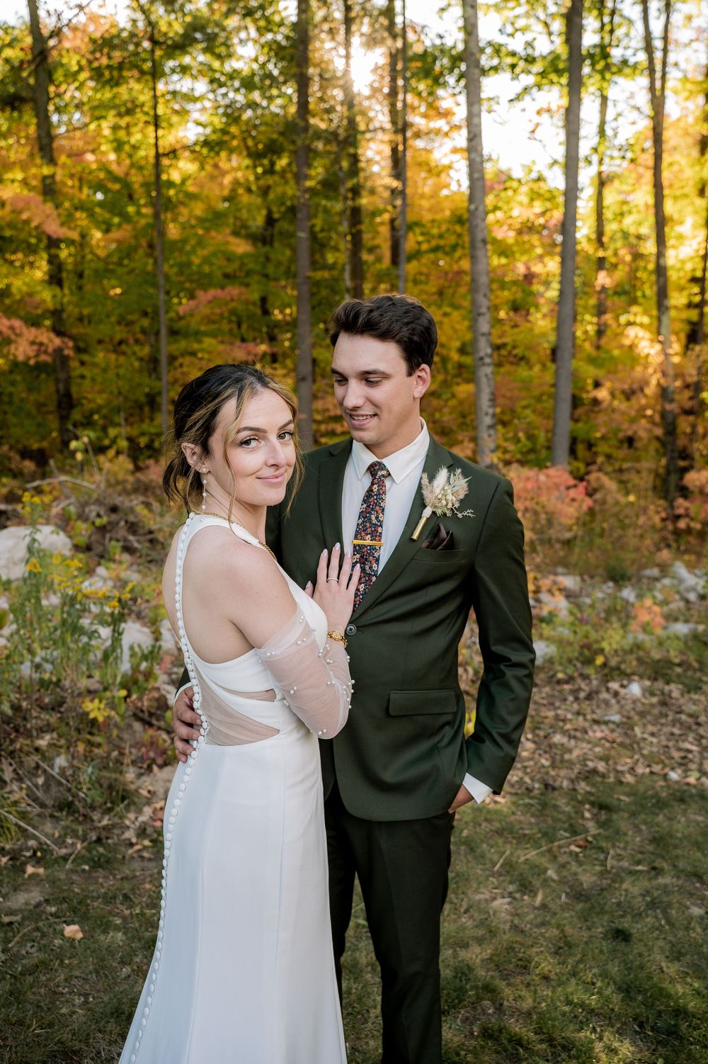 A couple shares a romantic moment in an autumn forest setting with golden sunlight filtering through the trees.