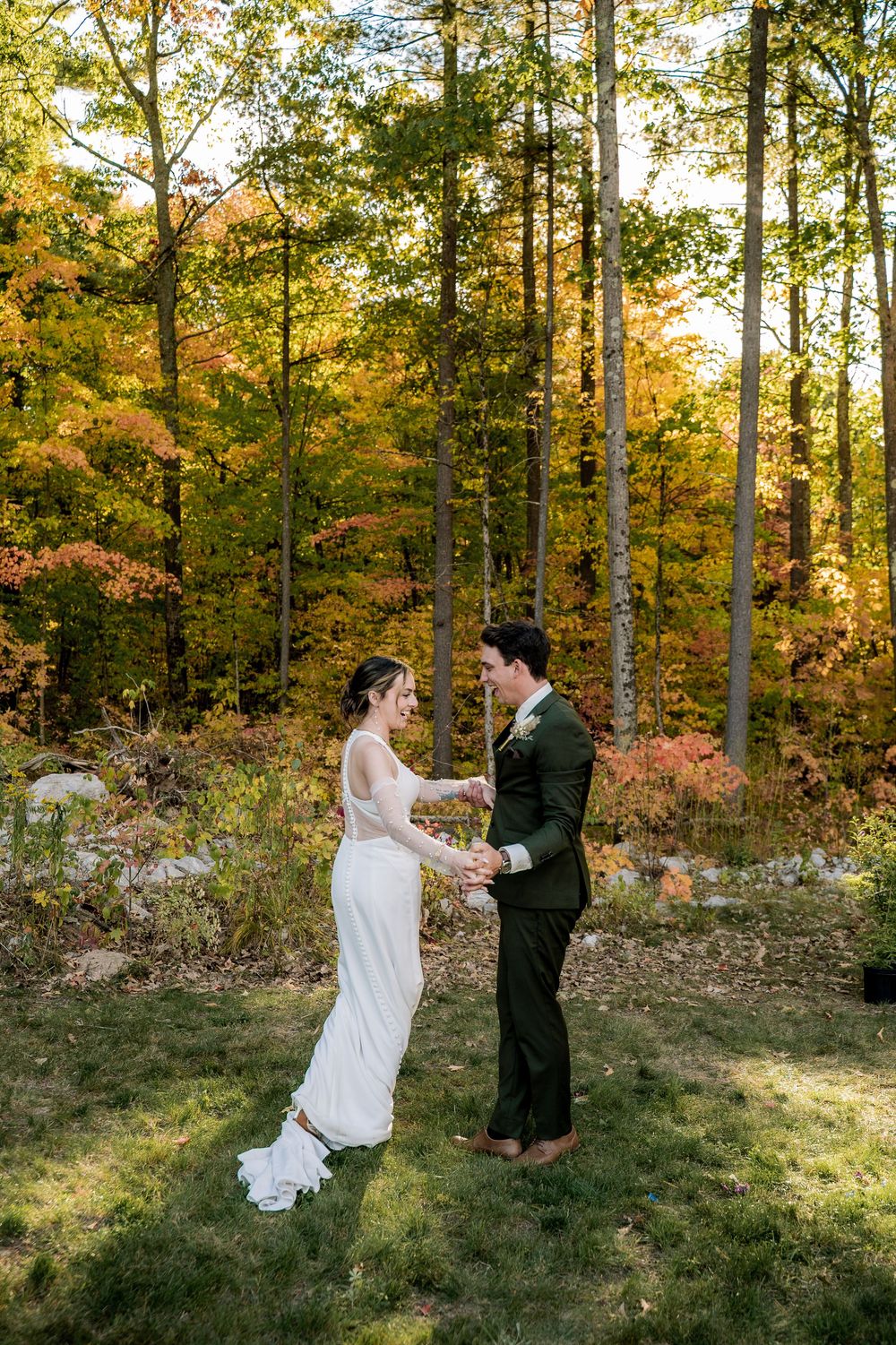 A couple shares a romantic first look moment in a sunlit autumn forest setting.