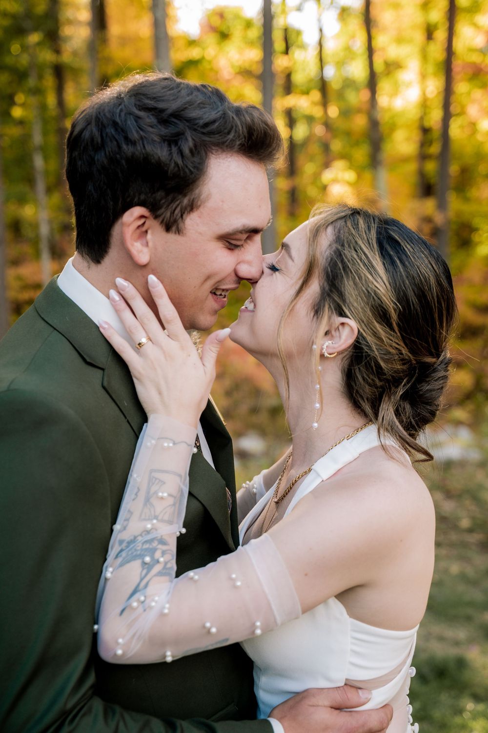 A romantic wedding couple shares intimate kisses in a sunlit autumn forest setting.