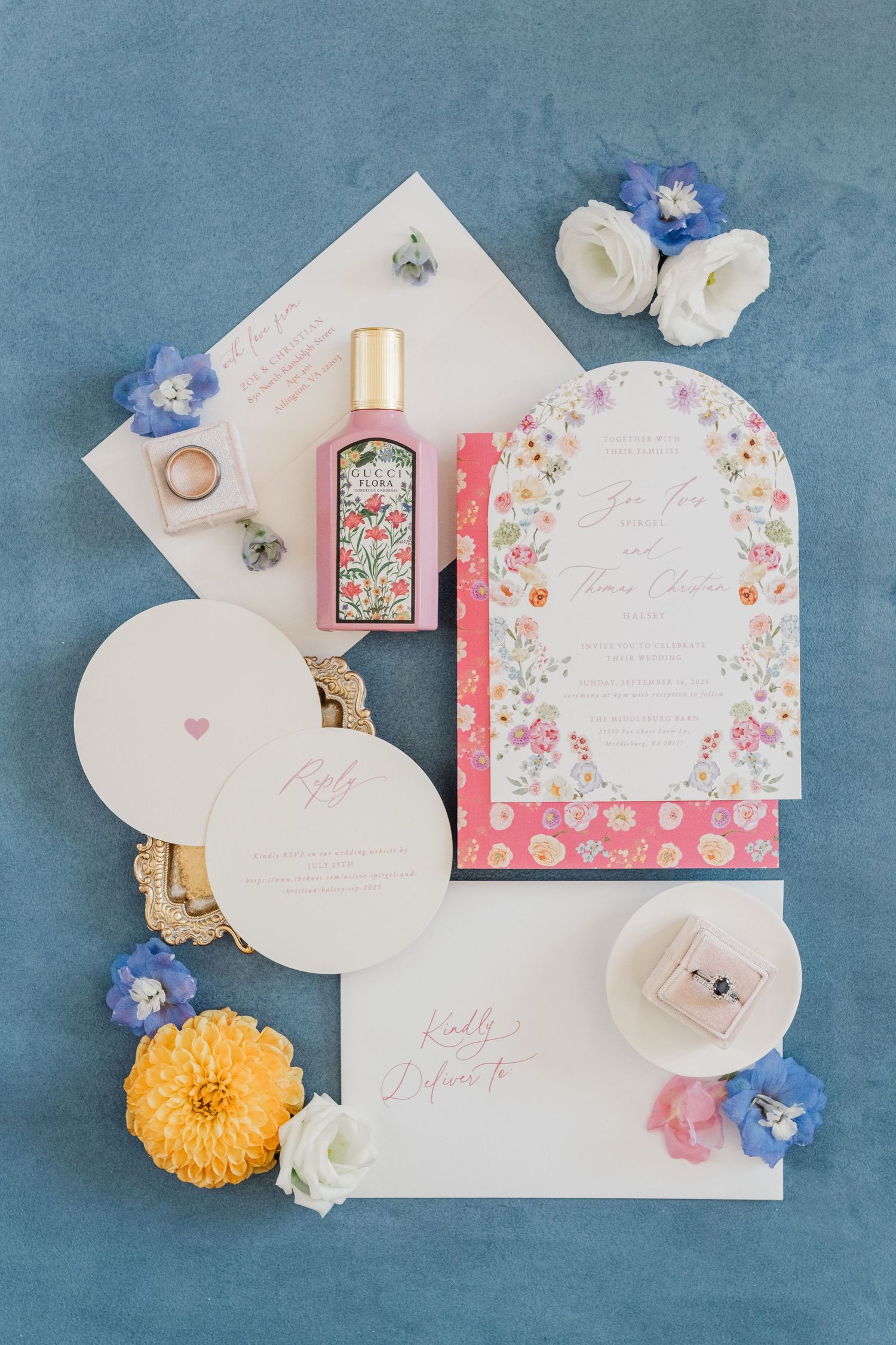 Elegant wedding invitation suite with floral patterns and decorative elements on blue backdrop.