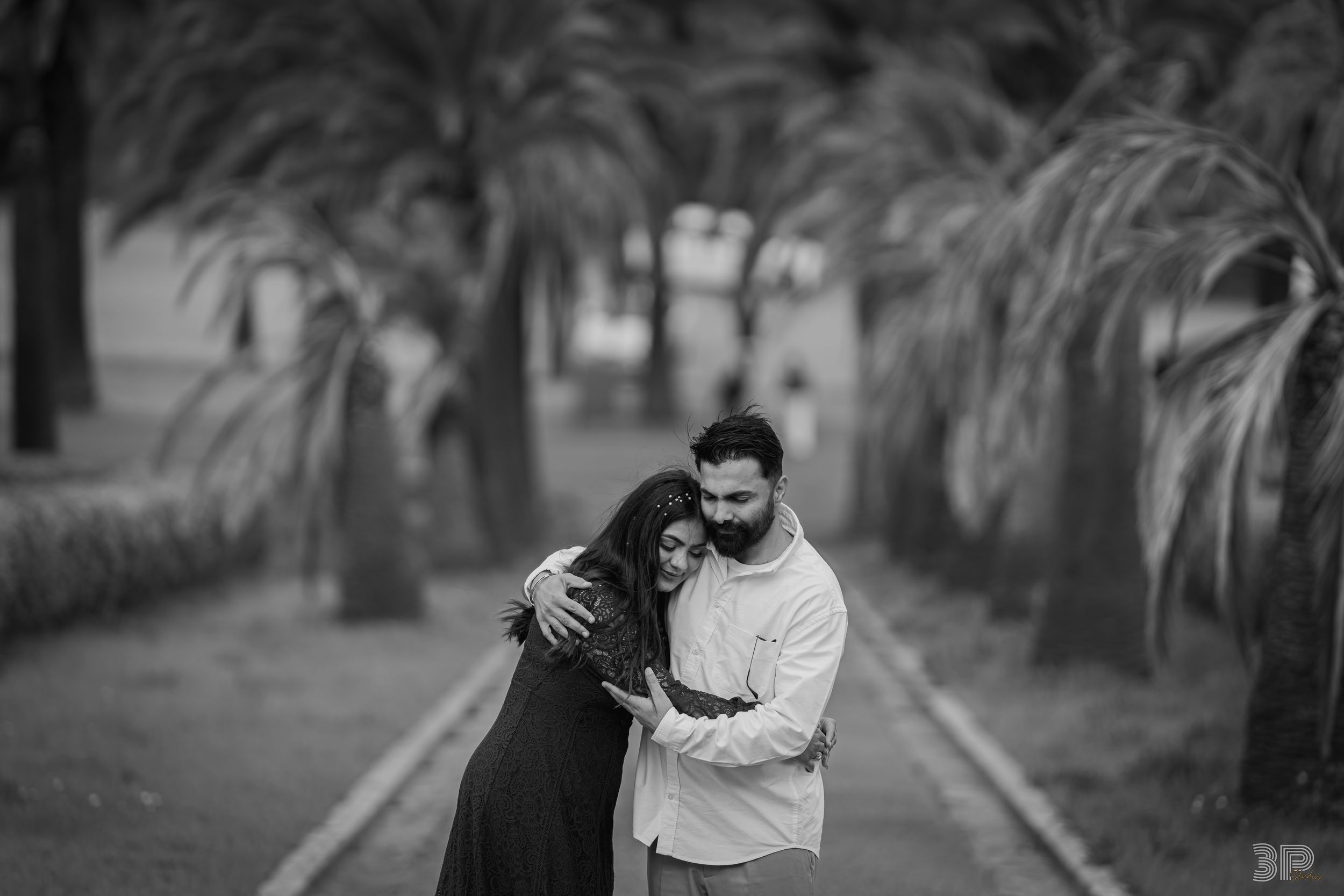 A couple embraces in a romantic pose against a blurred outdoor background.