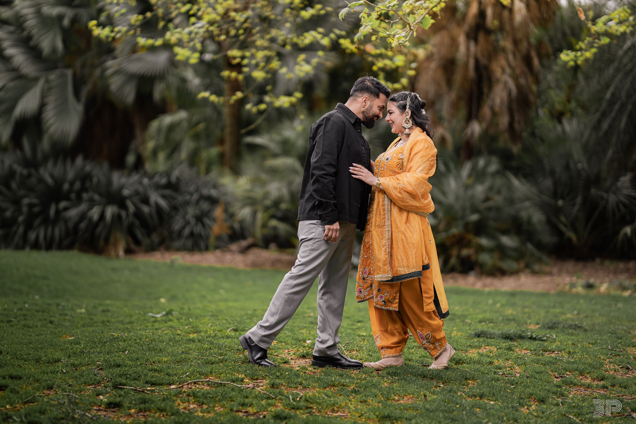 A couple embraces romantically in a lush garden setting during an autumn engagement photo session.