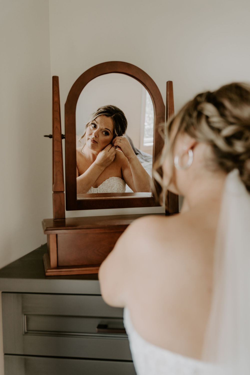 bride's reflection in mirror as she adds her earrings