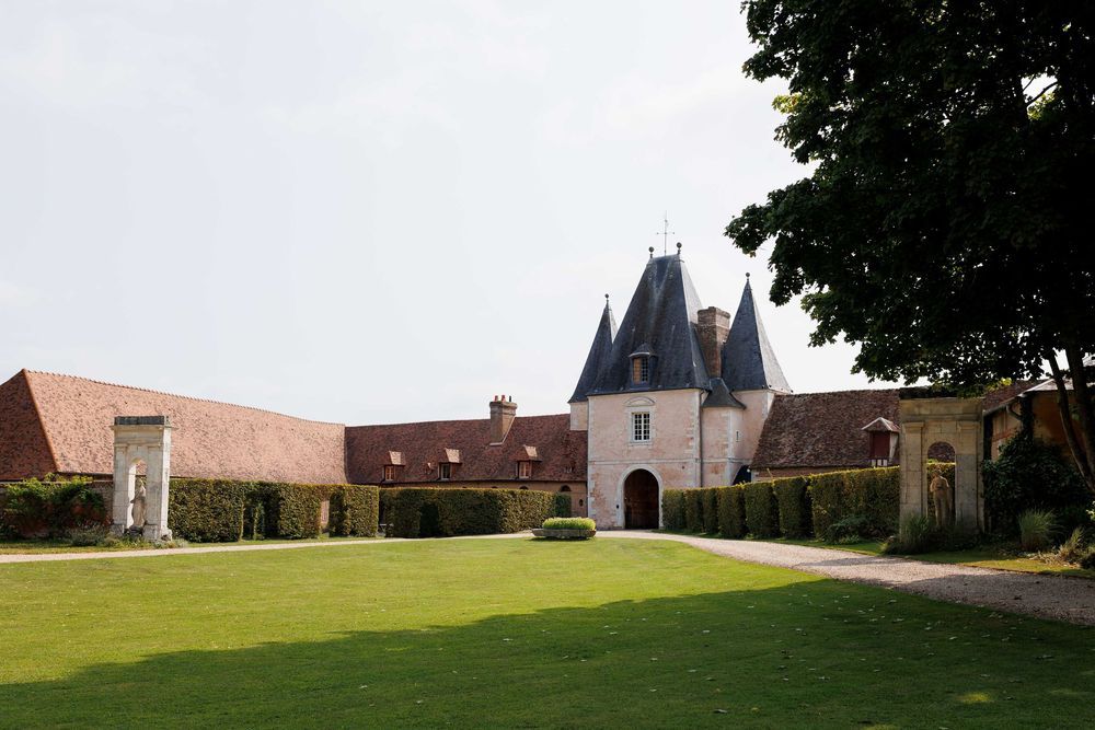 A panoramic view of a historic castle and its surrounding gardens with lush green lawns stretching into the distance.
