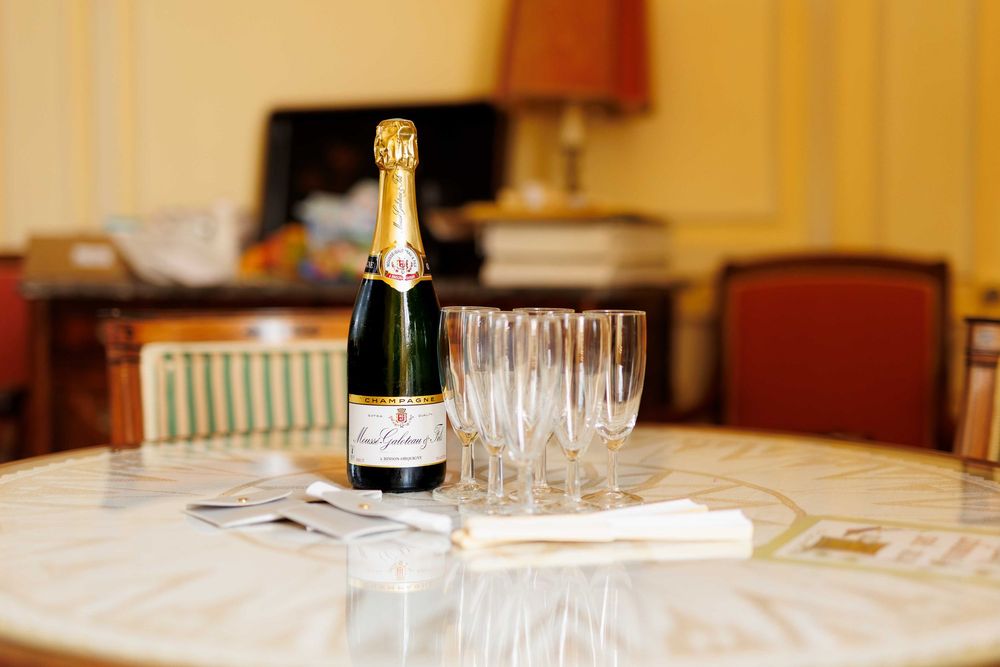 Champagne bottle and empty glasses arranged on a white tablecloth in a restaurant setting.