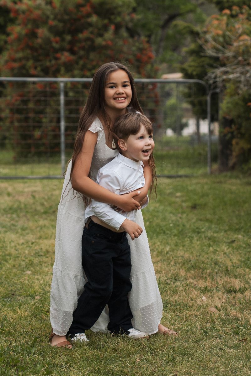 A series of candid outdoor photos showing playful interaction between two people on grass with autumn foliage in background in sydney