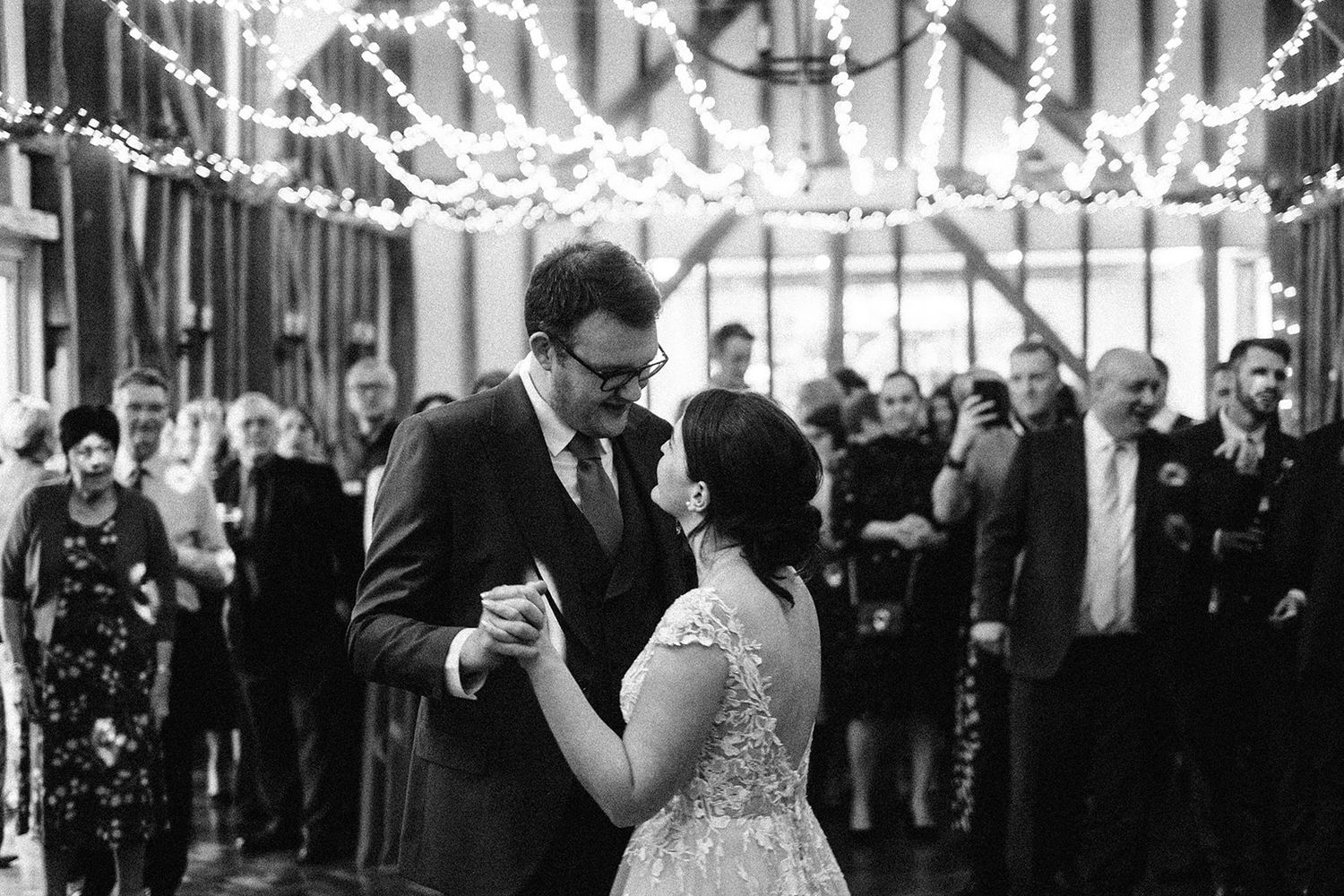 Crondon Park Wedding Venue - Guests dance and celebrate under elegant string lights at an indoor reception venue.