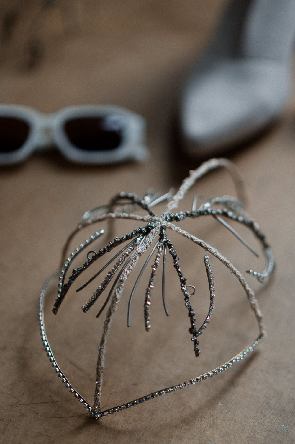 A delicate silver spider-shaped hair accessory with rhinestone details shown in multiple angles on a beige surface.
