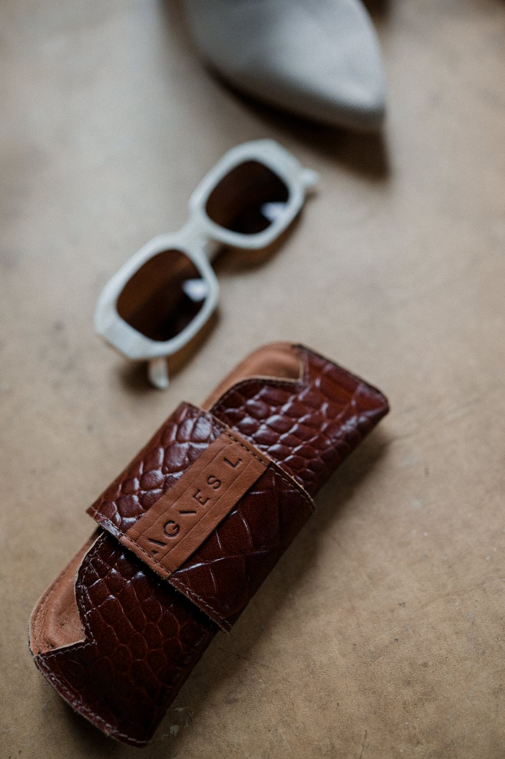 Close-up macro photos showing details of a brown leather watch strap with crocodile texture pattern and metal buckle.