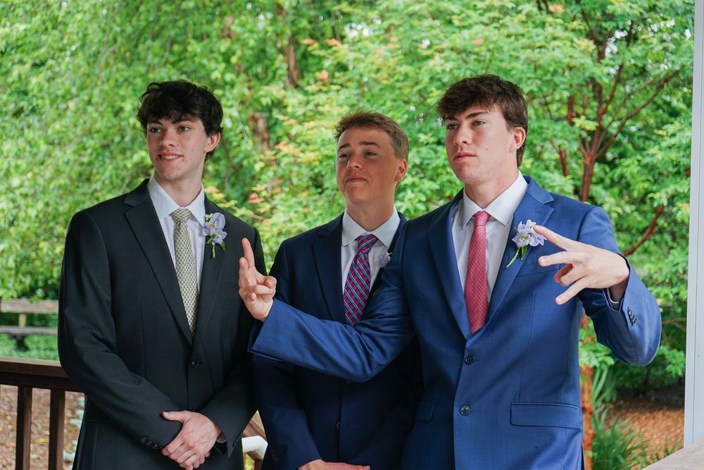 A group of formally dressed people share a candid moment while standing on an outdoor deck.