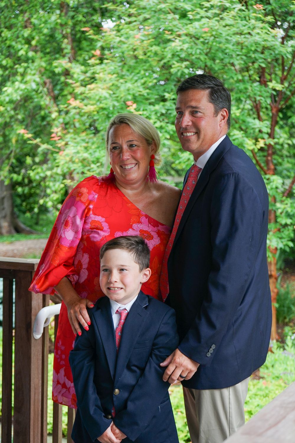 Family shares joyful laughter together on wooden deck surrounded by lush green foliage.