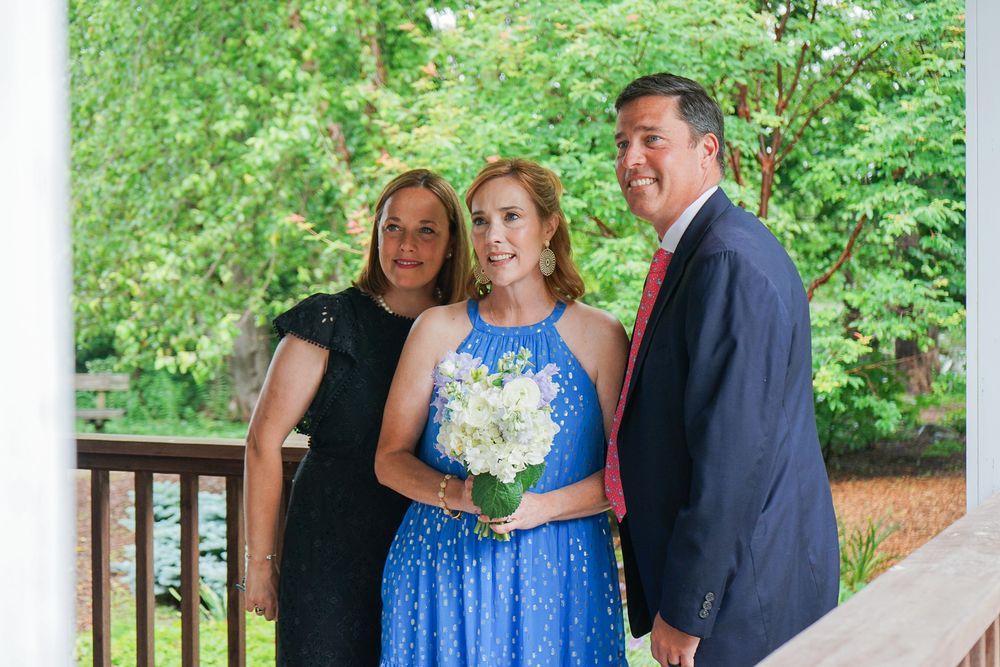 A group gathers on a wooden deck surrounded by lush greenery during an outdoor celebration.