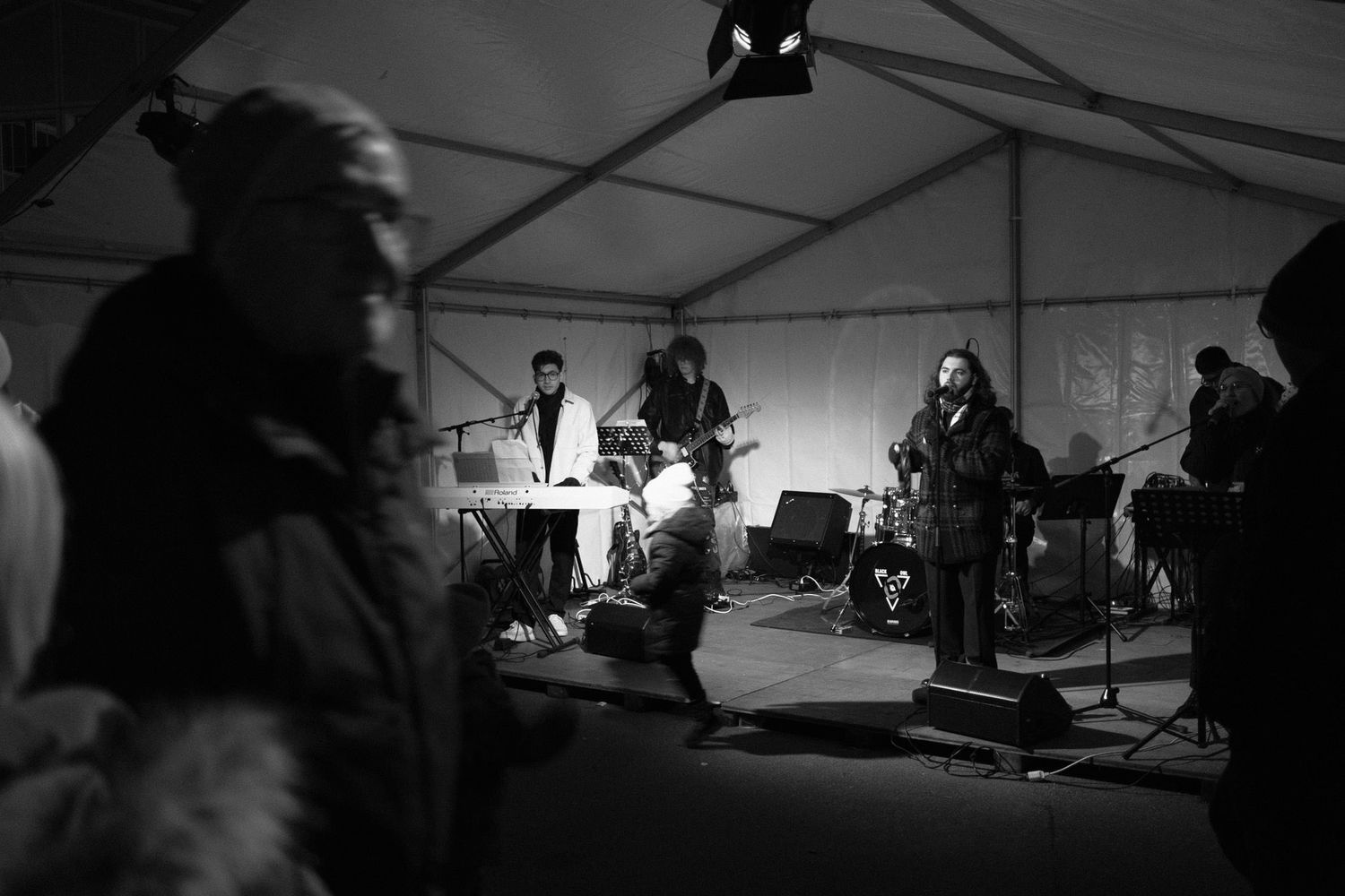 Silhouettes of performers on stage under dramatic lighting in a large tent.