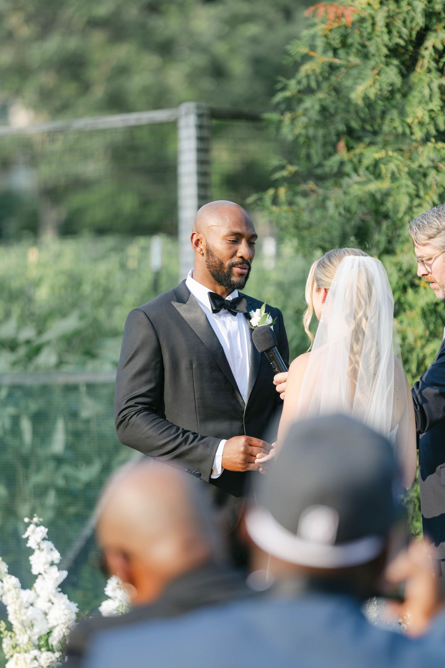 A couple shares an intimate moment during their outdoor wedding ceremony surrounded by greenery and guests. - Elawa Farm
