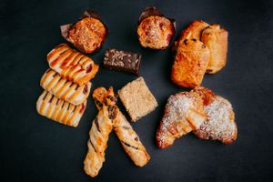 Assorted freshly baked pastries and breads arranged on dark background.