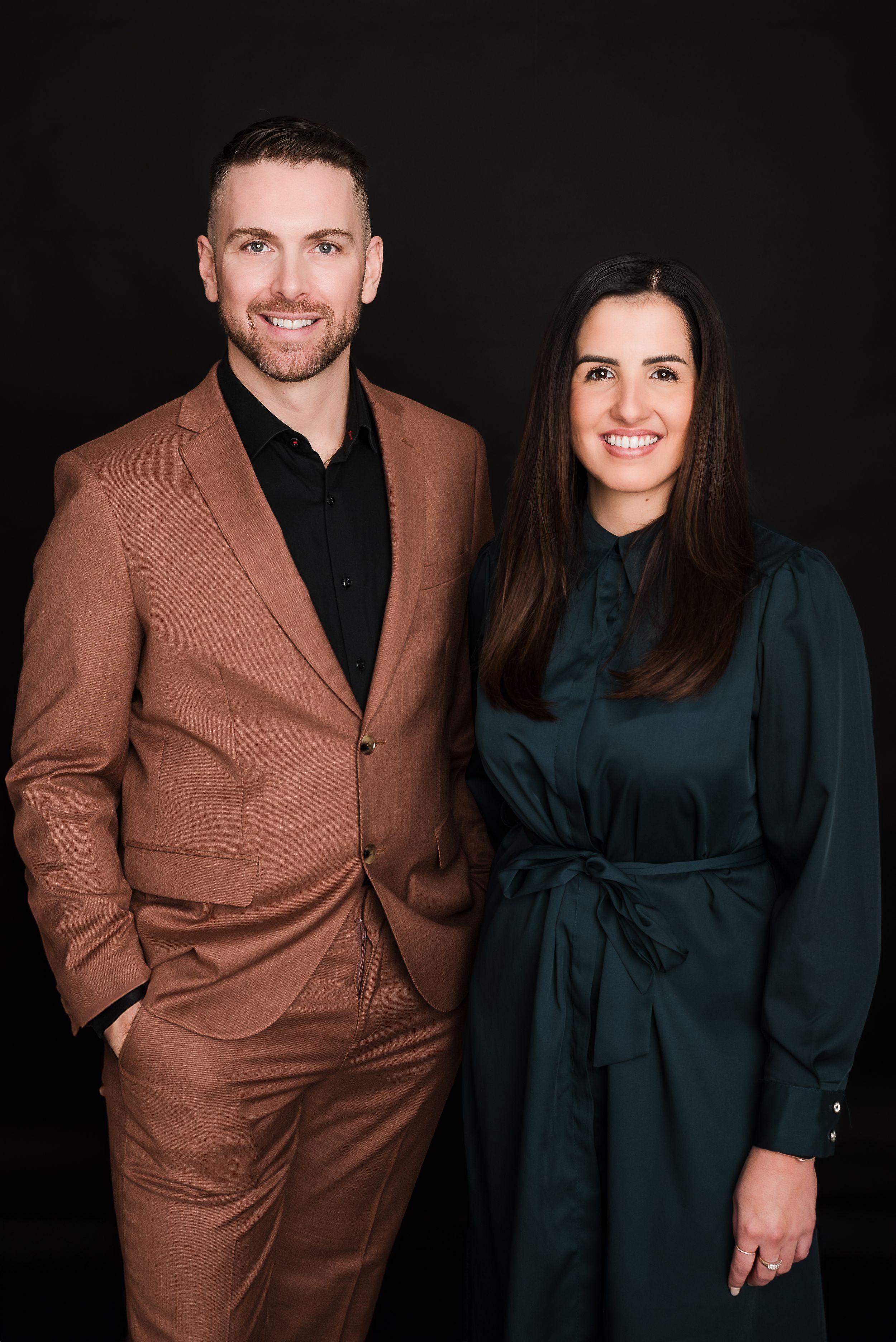 Studio portrait of couple in formal attire against black background.