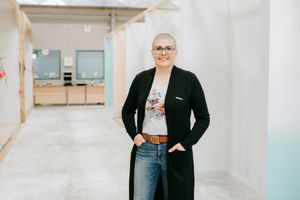 Casual portrait of person wearing black cardigan and jeans in white hallway.