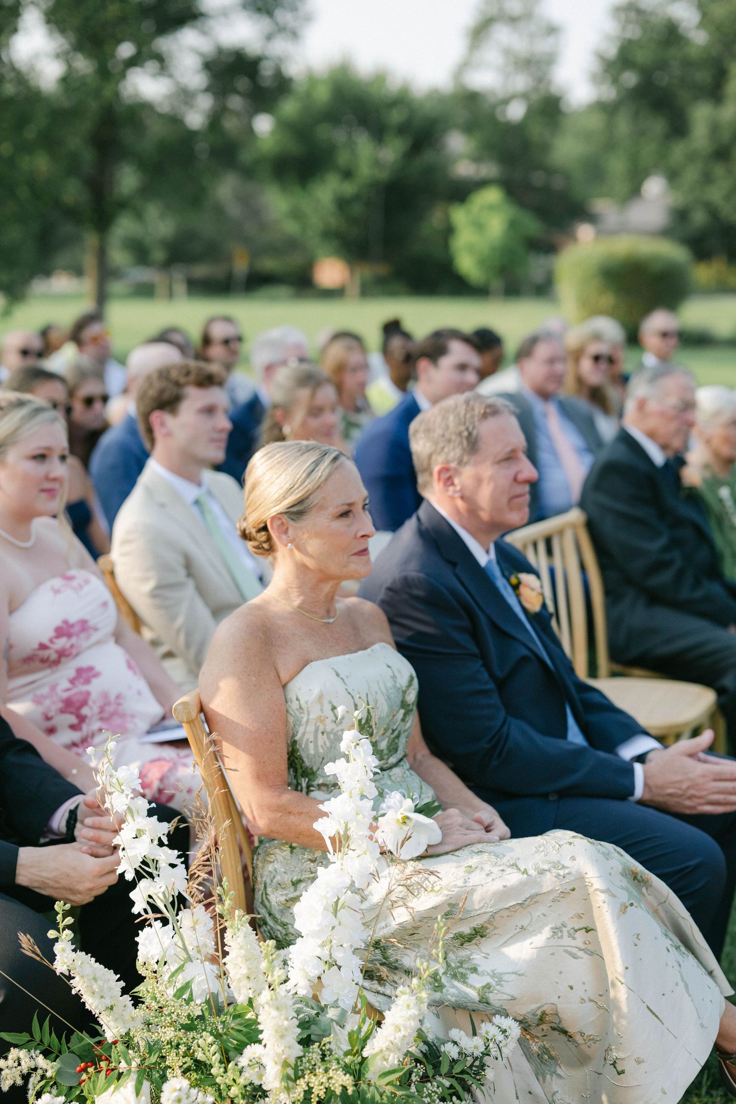 Groomsmen in black tuxedos stand in line on a grassy lawn during an outdoor wedding. - Elawa Farm
