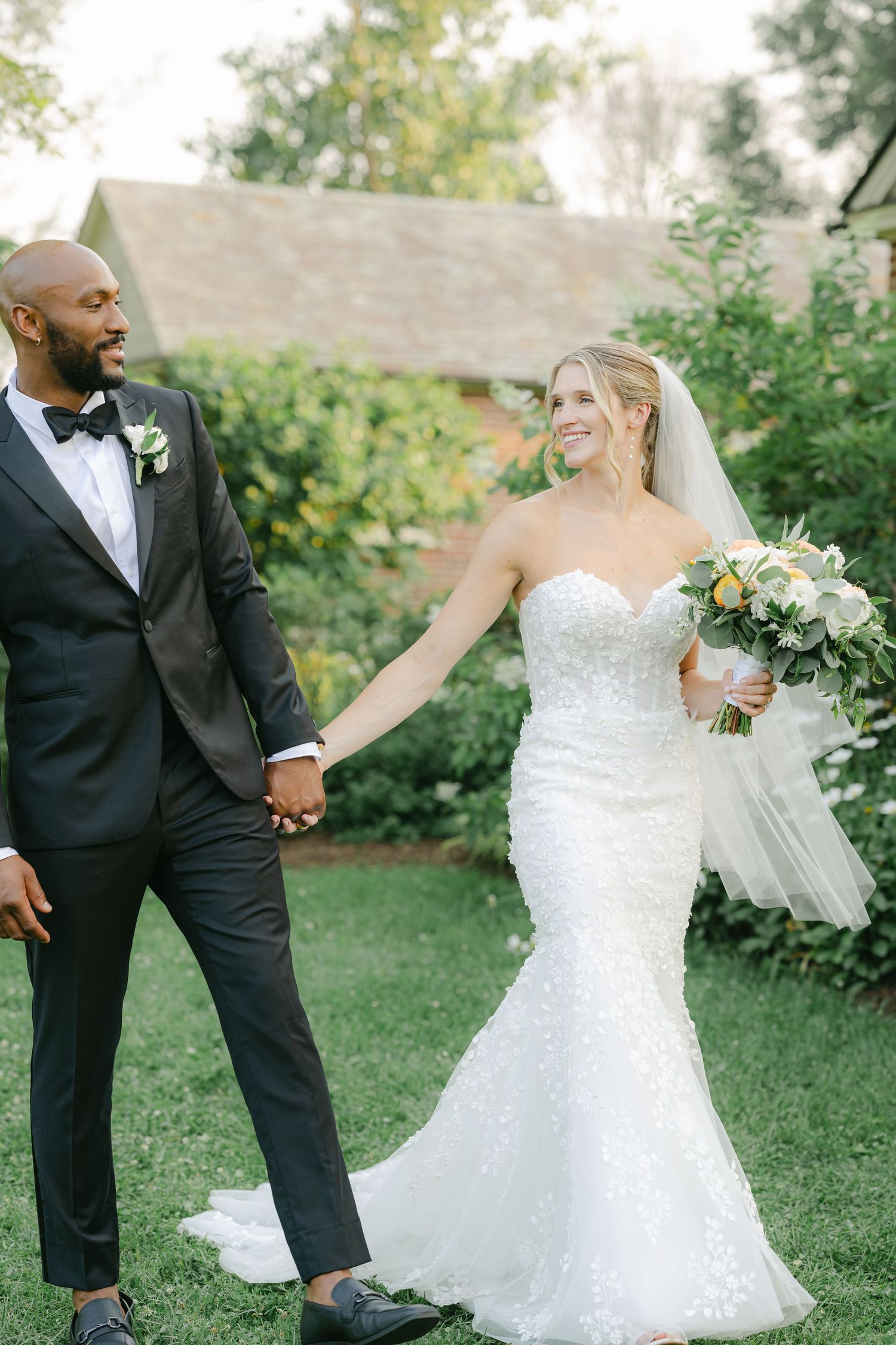 A bride and groom dance together on a lush green lawn during their wedding celebration. - Elawa Farm